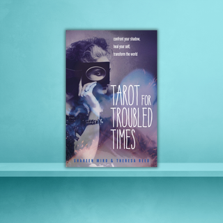 Book cover of 'Tarot for Troubled Times' with a person holding a tarot card on a blue background